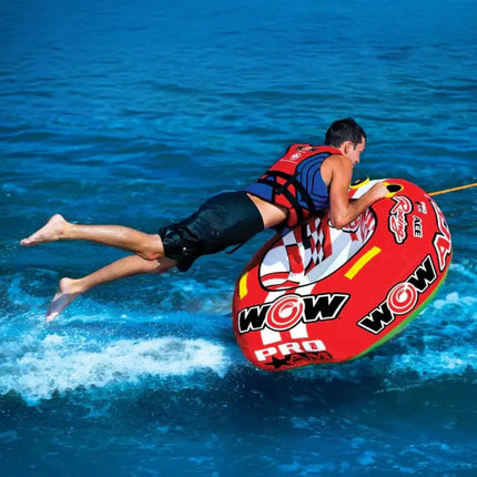 Man in life vest on red and white inflatable tube being pulled across blue water