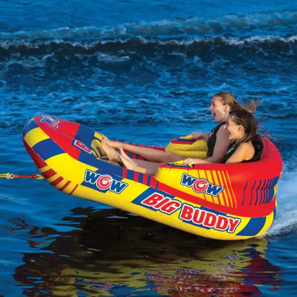 Two women on a red, yellow, and blue inflatable towable tube on the water