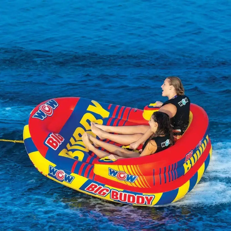 Two people riding a red, yellow, and blue inflatable tube on the water
