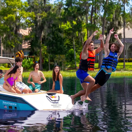 Two men in life vests jump from a boat into the water, while four people watch from the boat