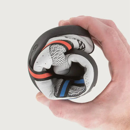 Hand holding a rolled-up white, black, red, and blue athletic shoe