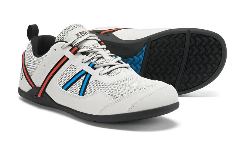 White Xero Shoes with red and blue stripes on the side, black soles, and a black pull tab